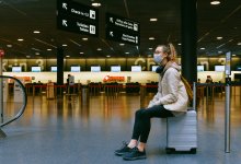 Jeune femme assise sur sa valise dans un aéroport