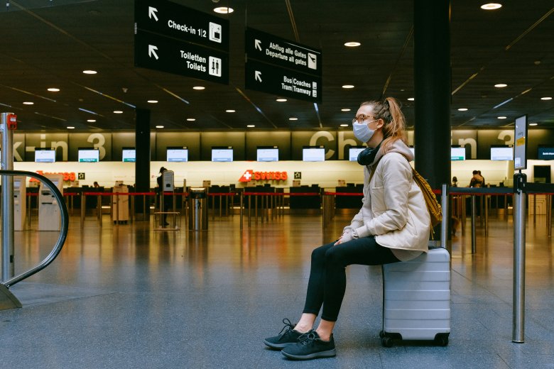 Jeune femme assise sur sa valise dans un aéroport