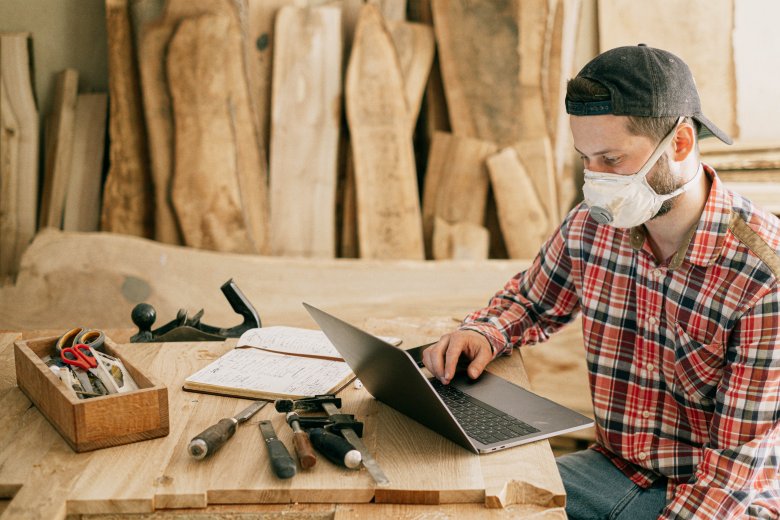 Un homme devant son ordinateur dans un atelier de bois